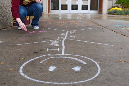 Lake City graduate student Carrie Prolega chalks the sidewalk in front of Anspach Hall for the National Day on Writing on Oct. 20, 2015. Kaiti Chritz | Photo Editor